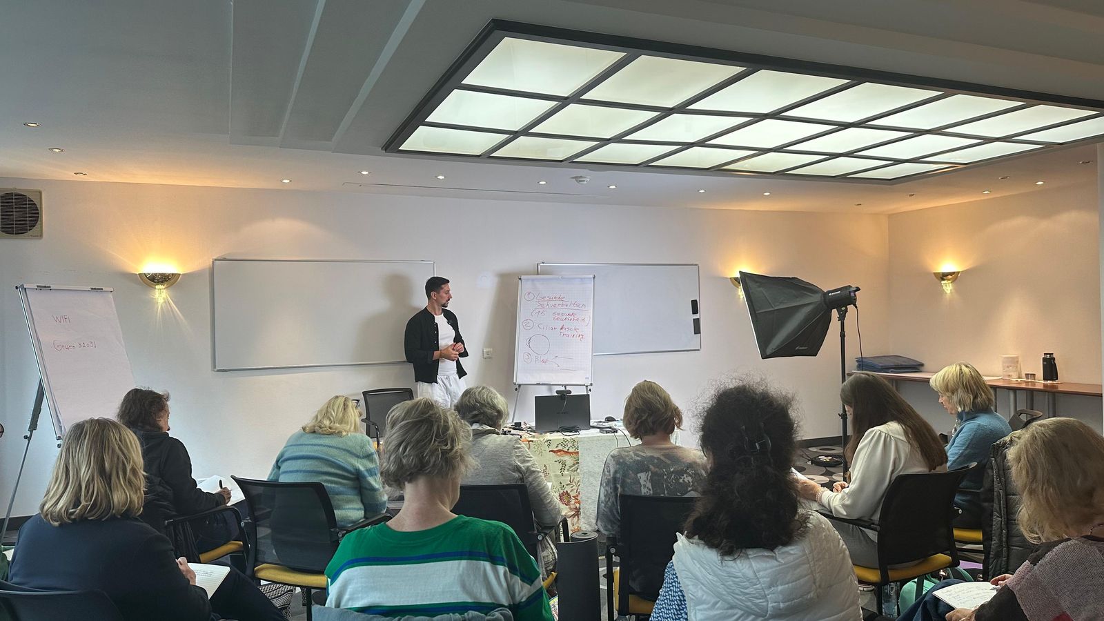 Seminarraum in Frankfurt: Teilnehmende sitzen vor dem Flipchart, Fedor Simonov unterrichtet