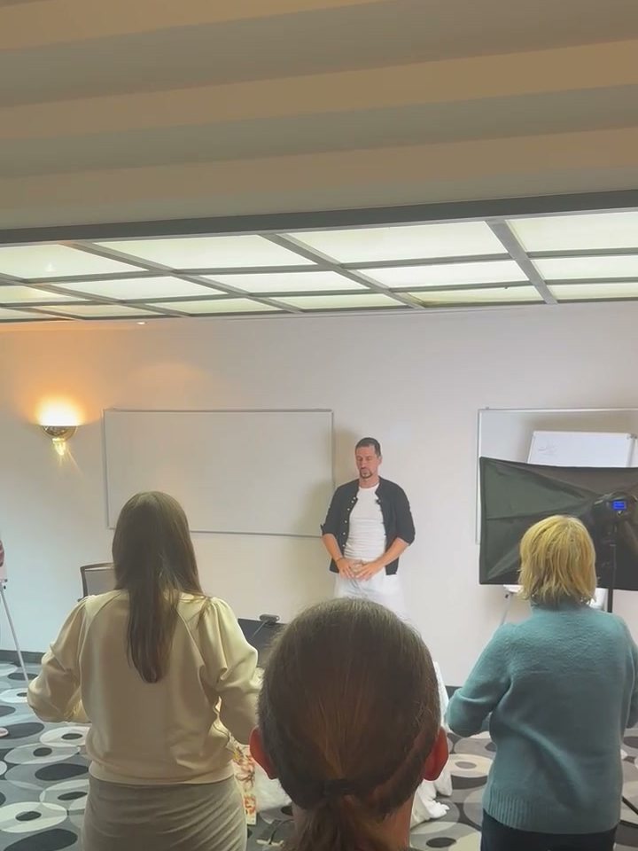 Teilnehmerinnen üben gemeinsam im Stehen, der Trainer steht vor der Gruppe